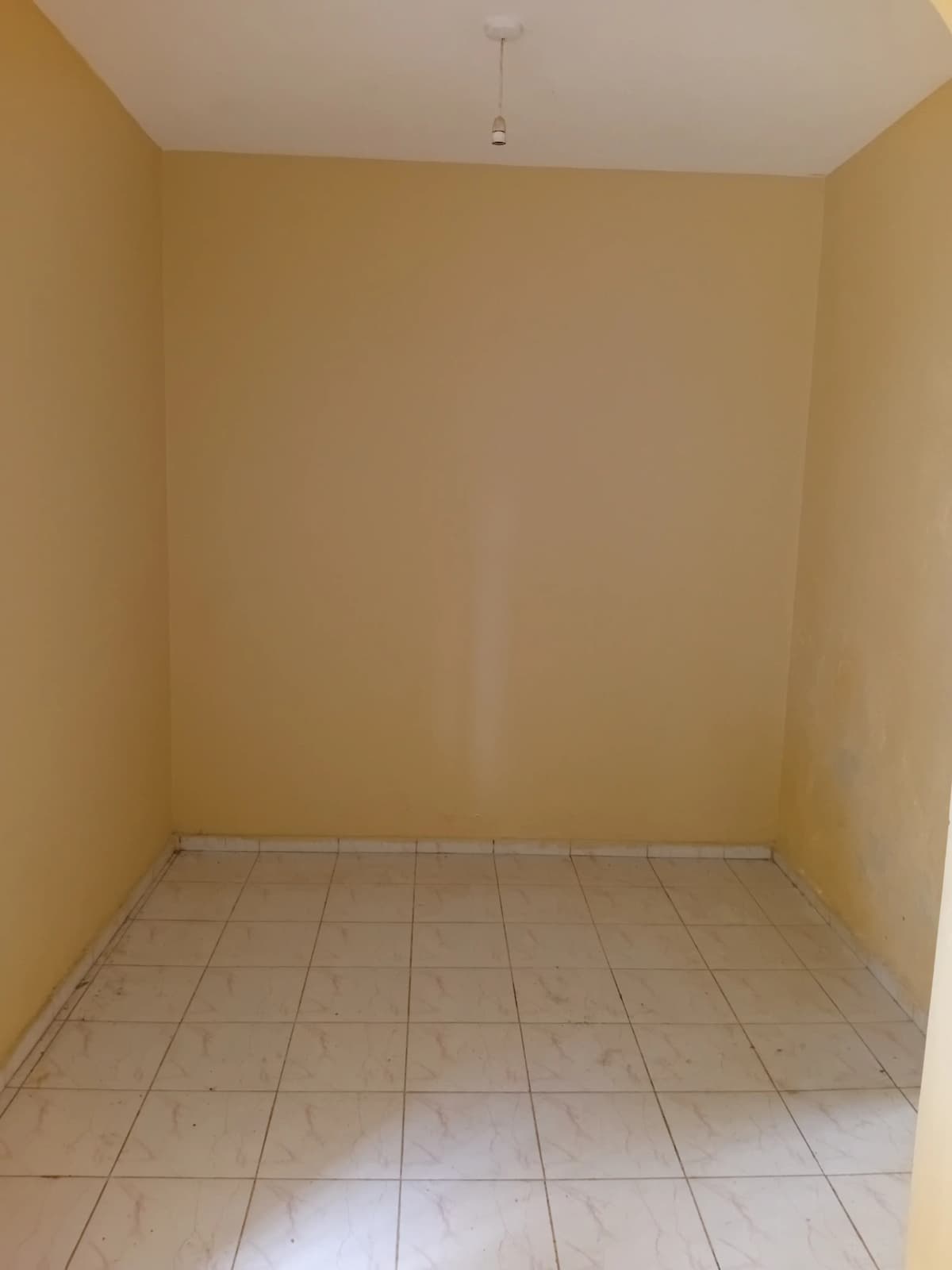Empty bedroom with tiled floor and yellow walls