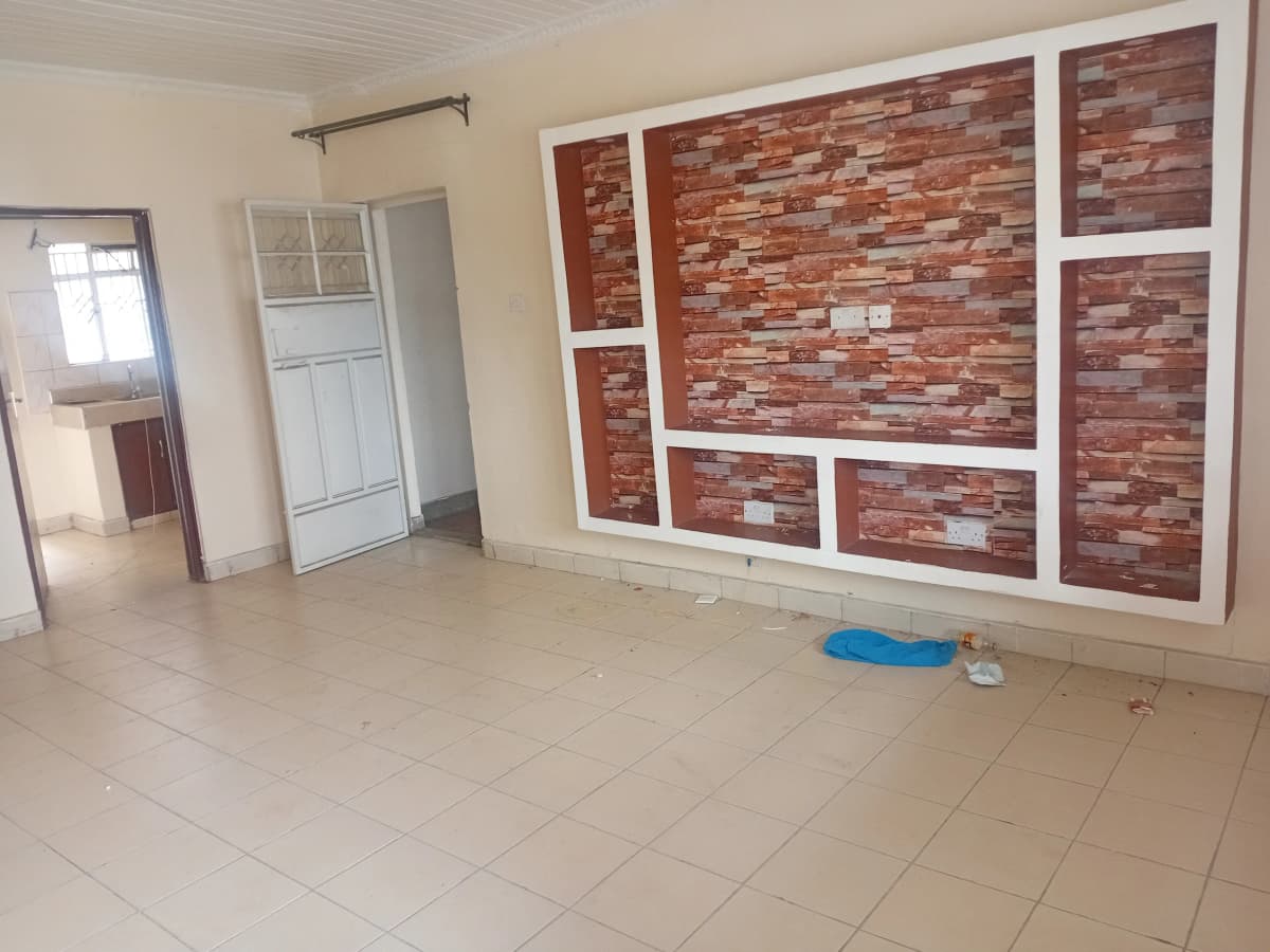 Empty living room with brick accent wall and tile flooring