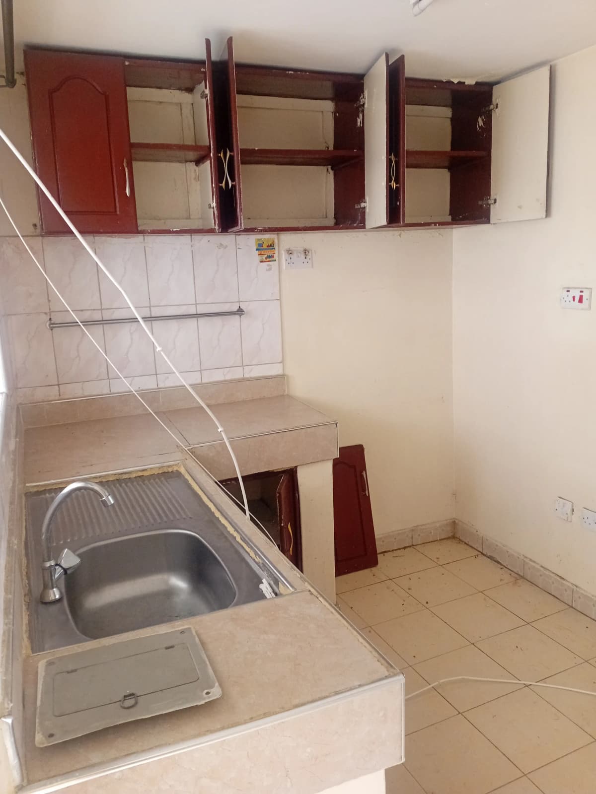 Compact kitchen with stainless steel sink and red wall cabinets