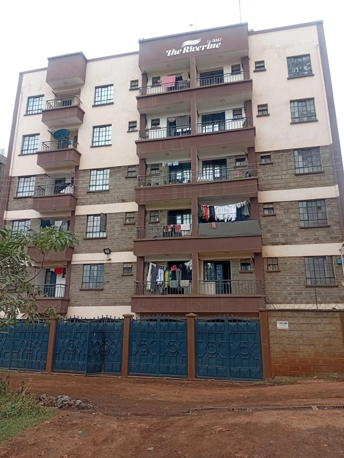 Multi-story residential building facade with balconies and parking gates