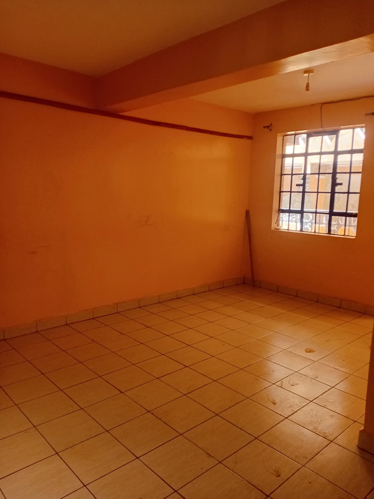 Empty bedroom with terracotta tiles and large window