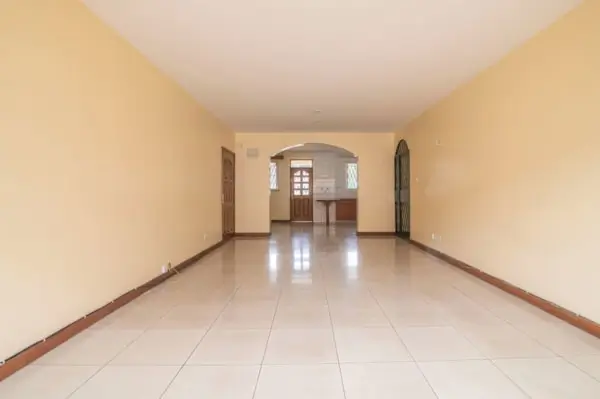 Empty tiled living room with arched doorway and entrance