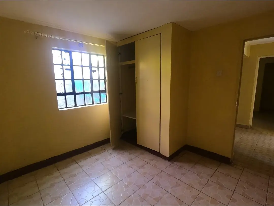 Sparse bedroom with wardrobe, barred window, tiled floor