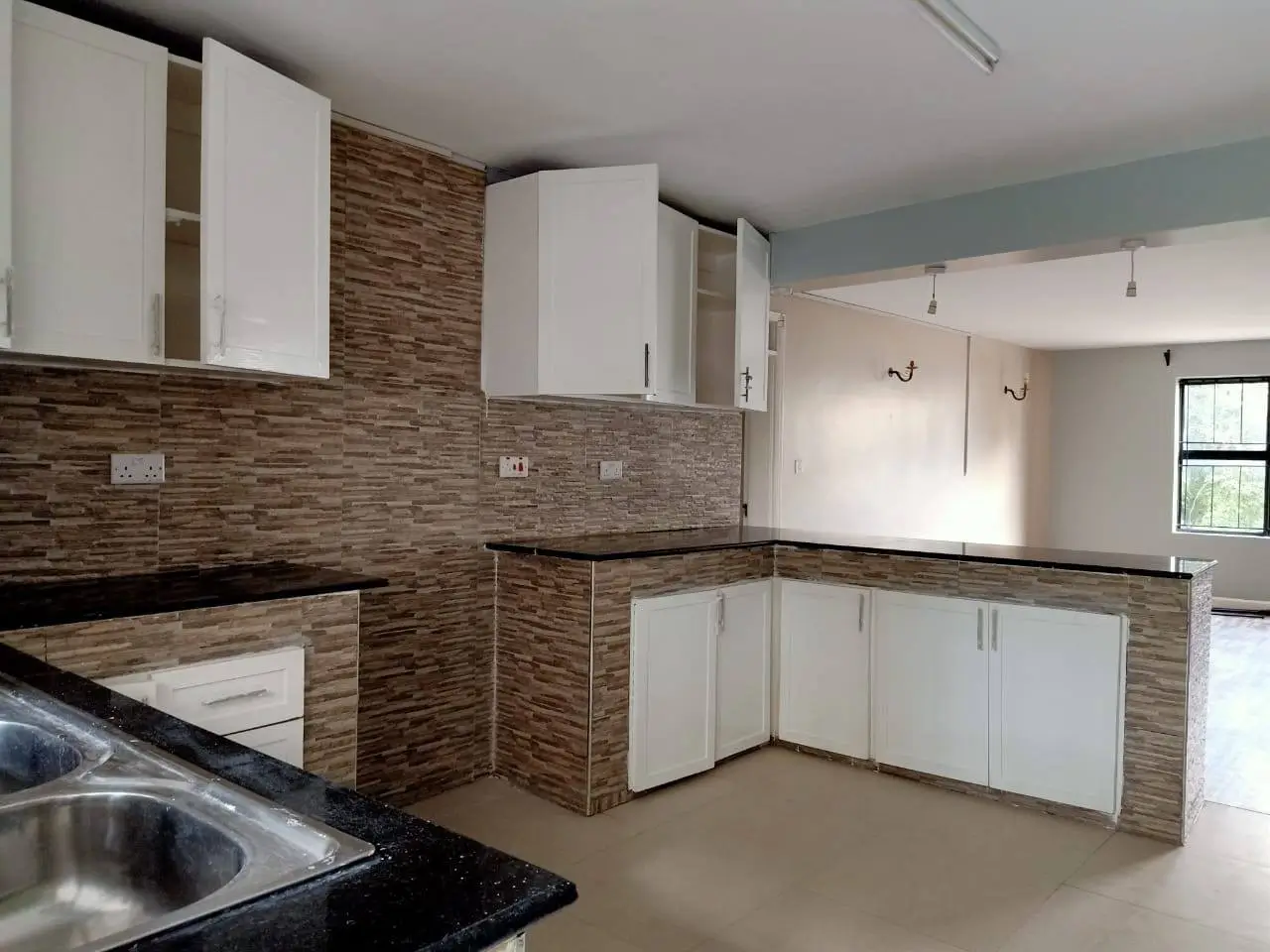 Modern kitchen with white cabinetry, brick backsplash, granite counters