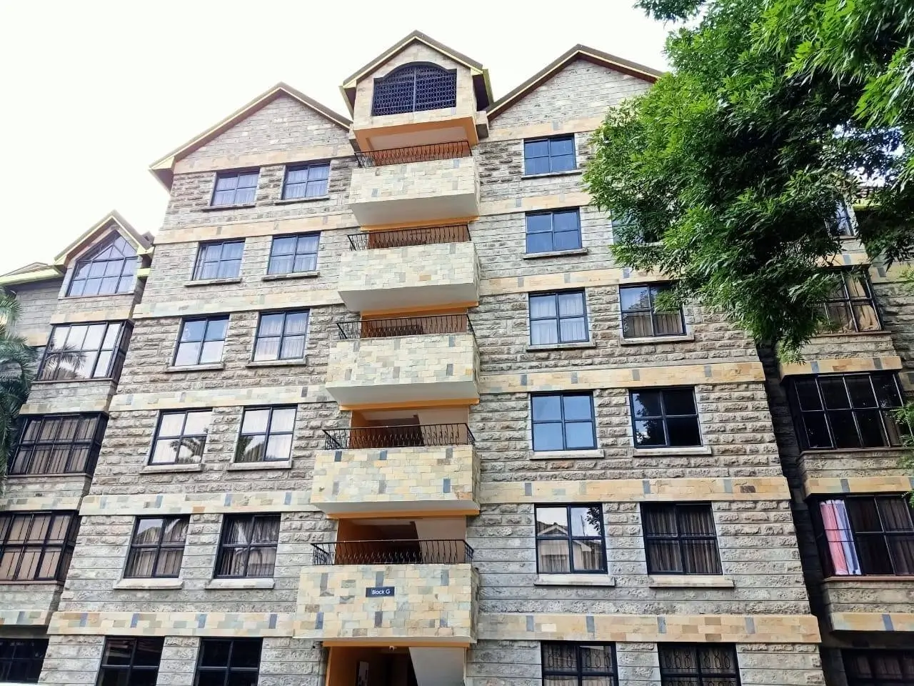 Modern multi-story residential building with stone facade and balconies