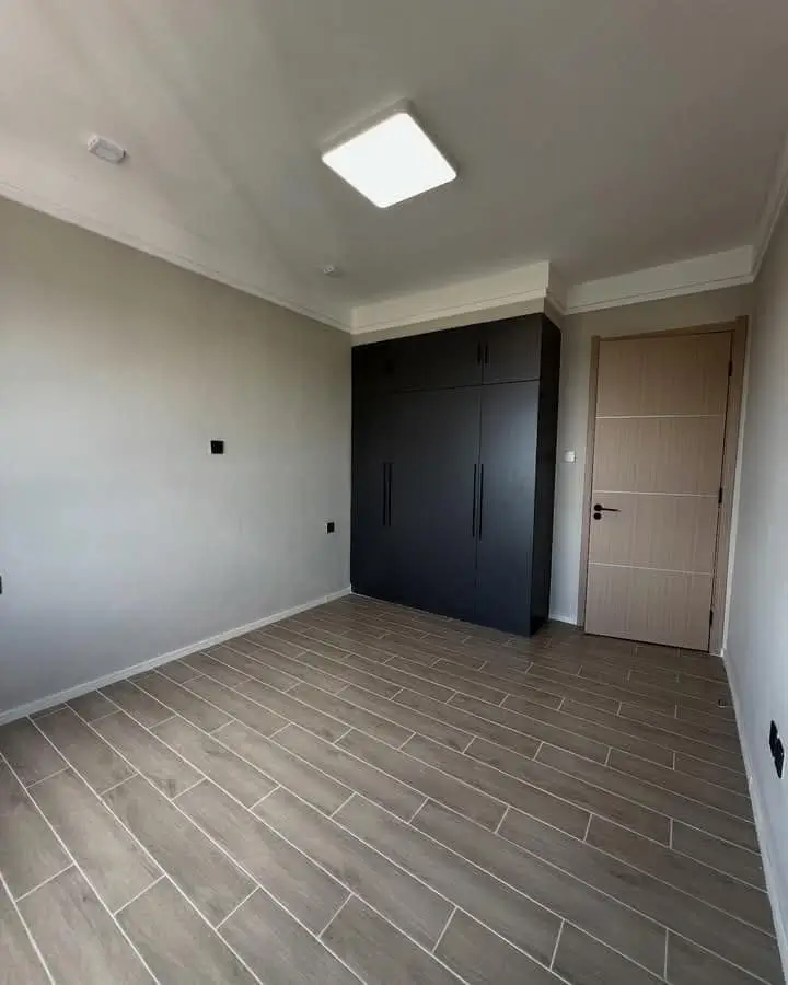 Empty bedroom with herringbone flooring and built-in wardrobe