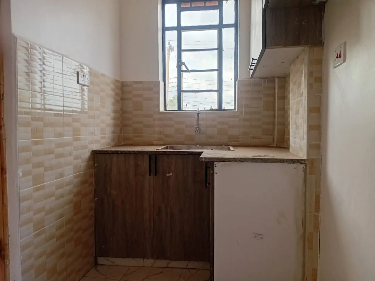 Compact kitchen with dark cabinetry and tiled walls