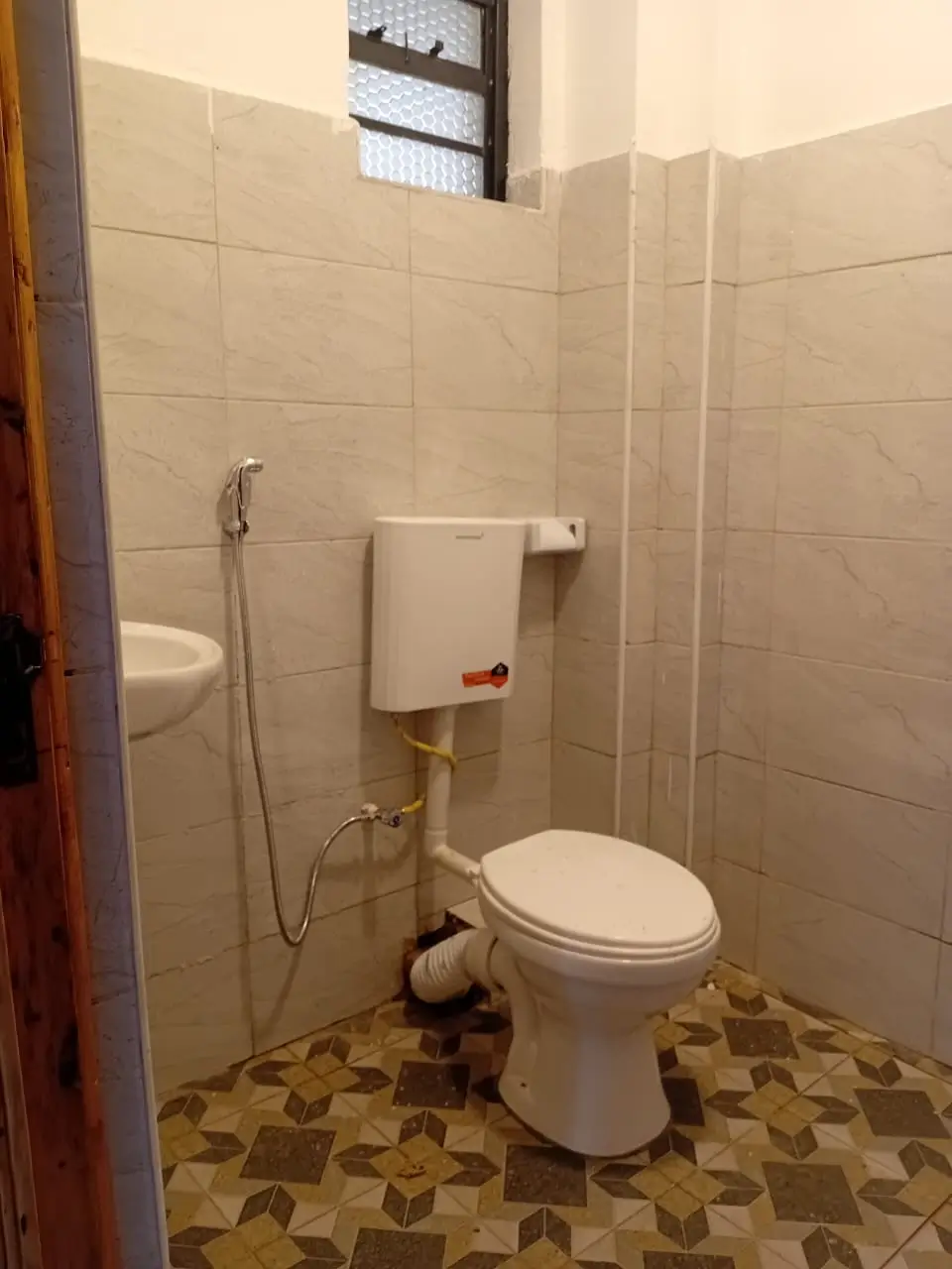 Compact bathroom with toilet, hand basin, tiled walls