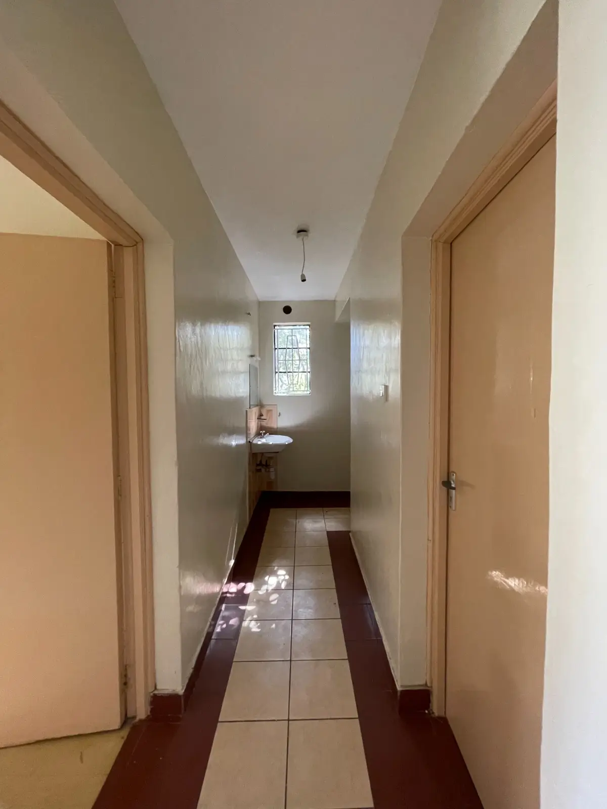 Long bright corridor with wooden doors and tiled flooring