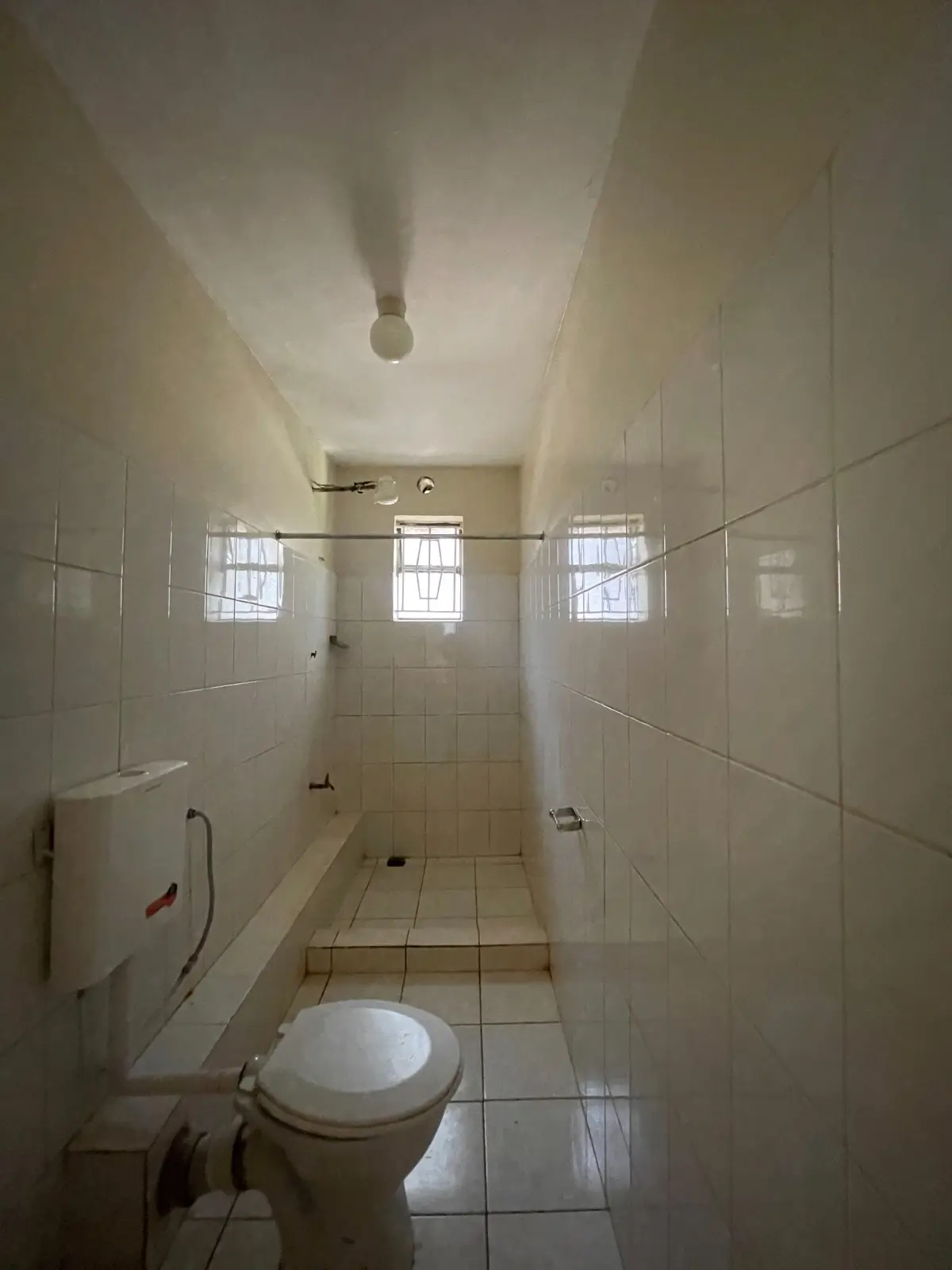Simple bathroom with toilet, sink, and tiled walls