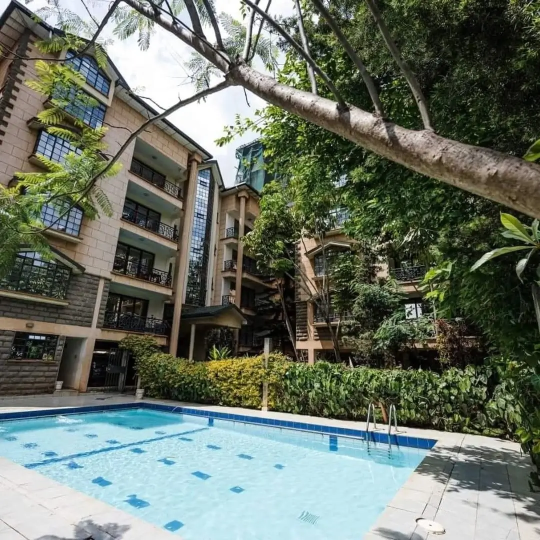 Resort-style swimming pool with lush landscaping and modern apartment building