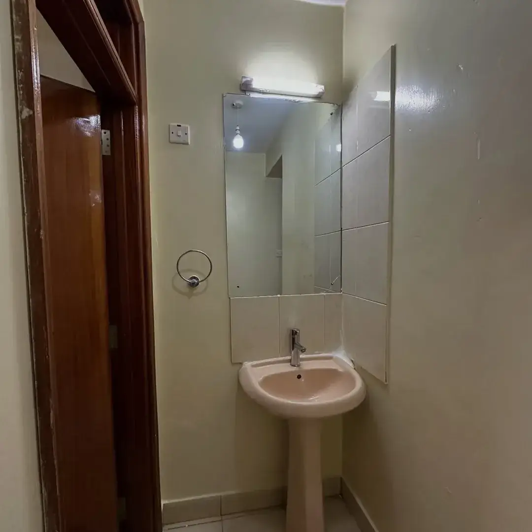 Compact bathroom with pedestal sink and glass shower enclosure