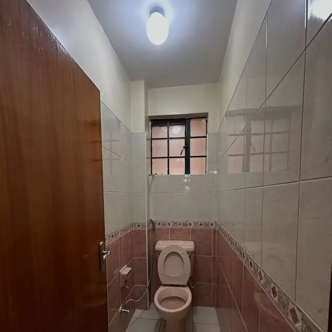 Compact bathroom with toilet, tiled walls, small window