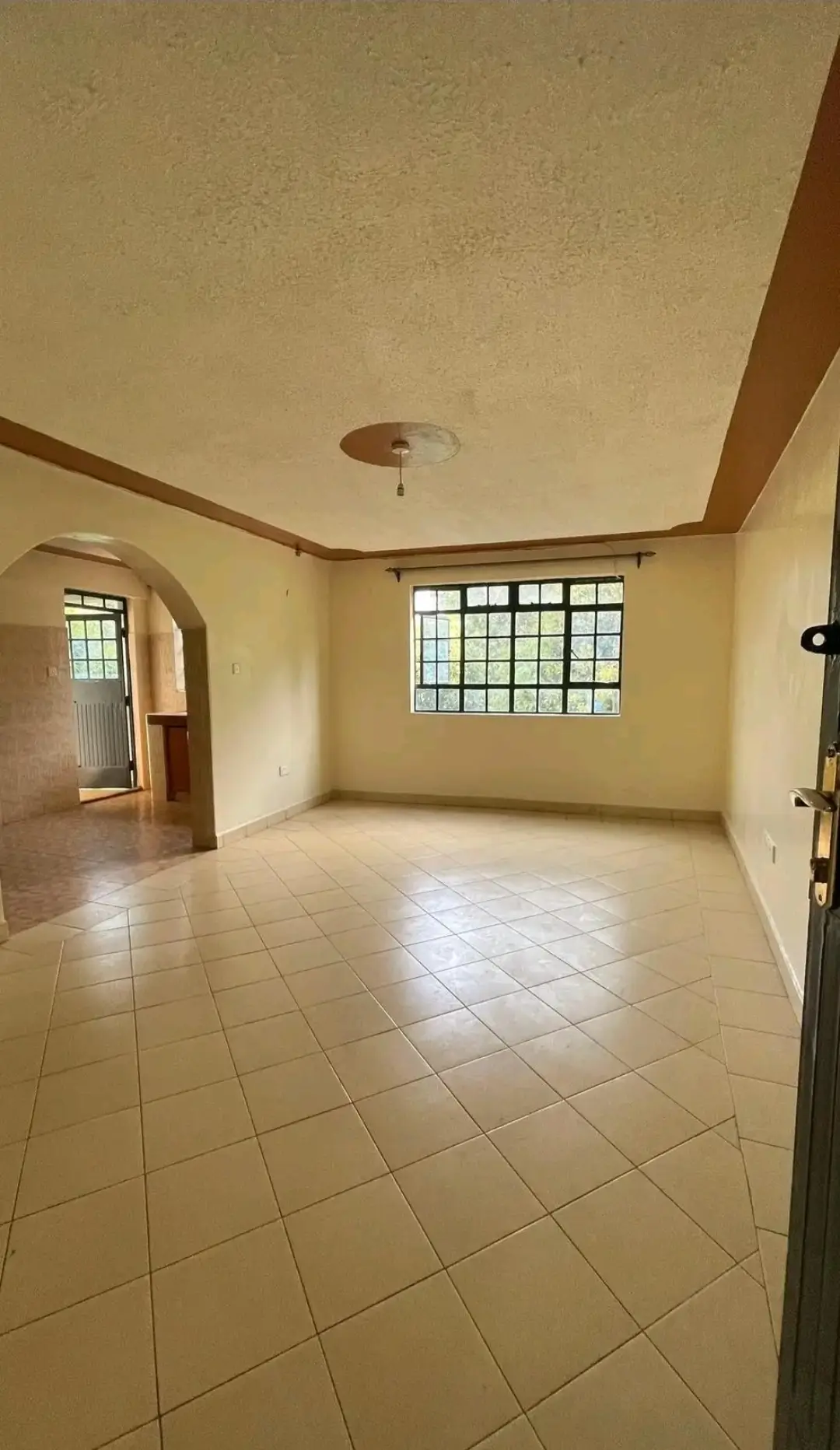 Spacious empty living room with tiled floors and natural light
