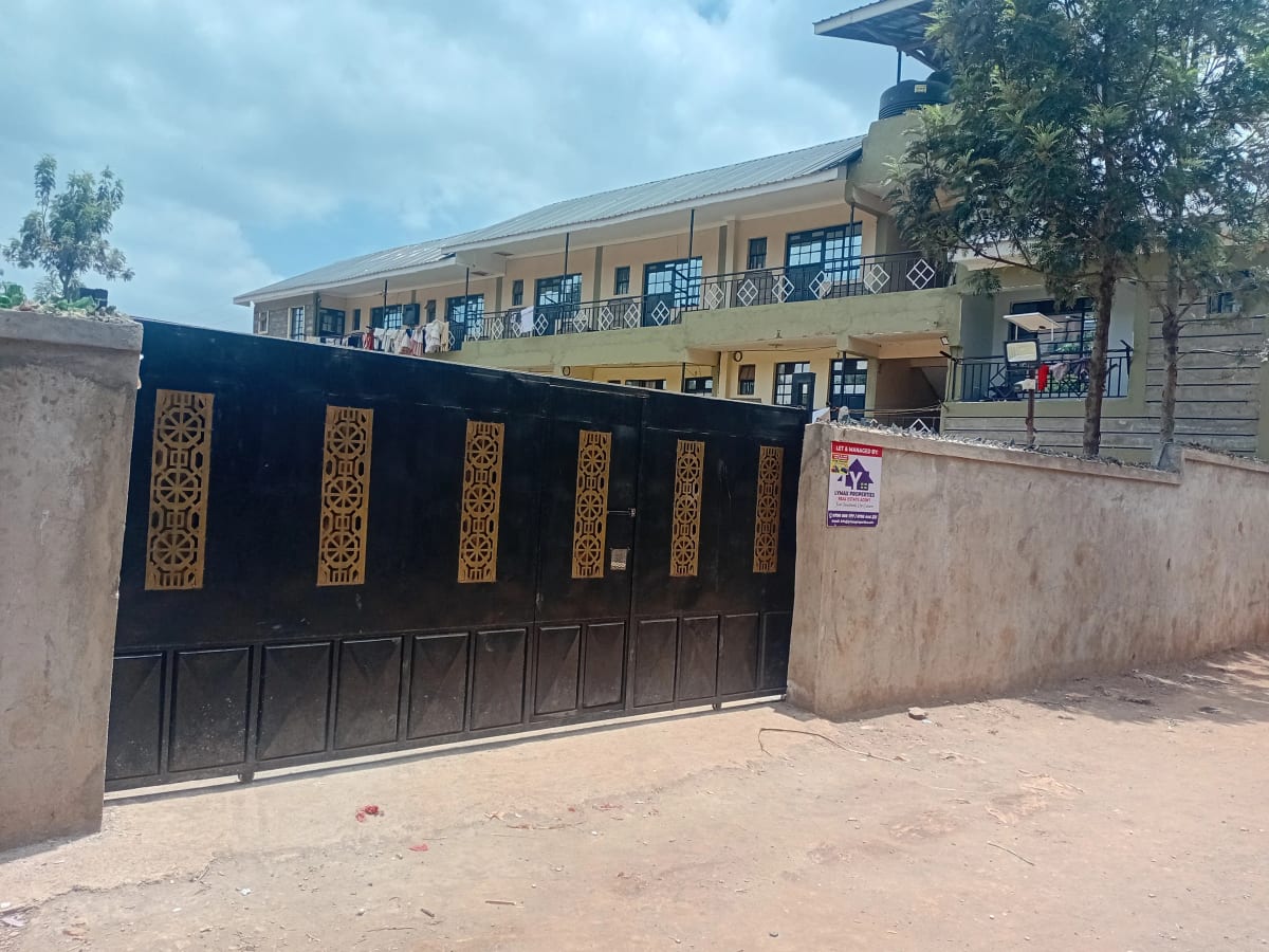 Black metal gate with compound wall and residential building