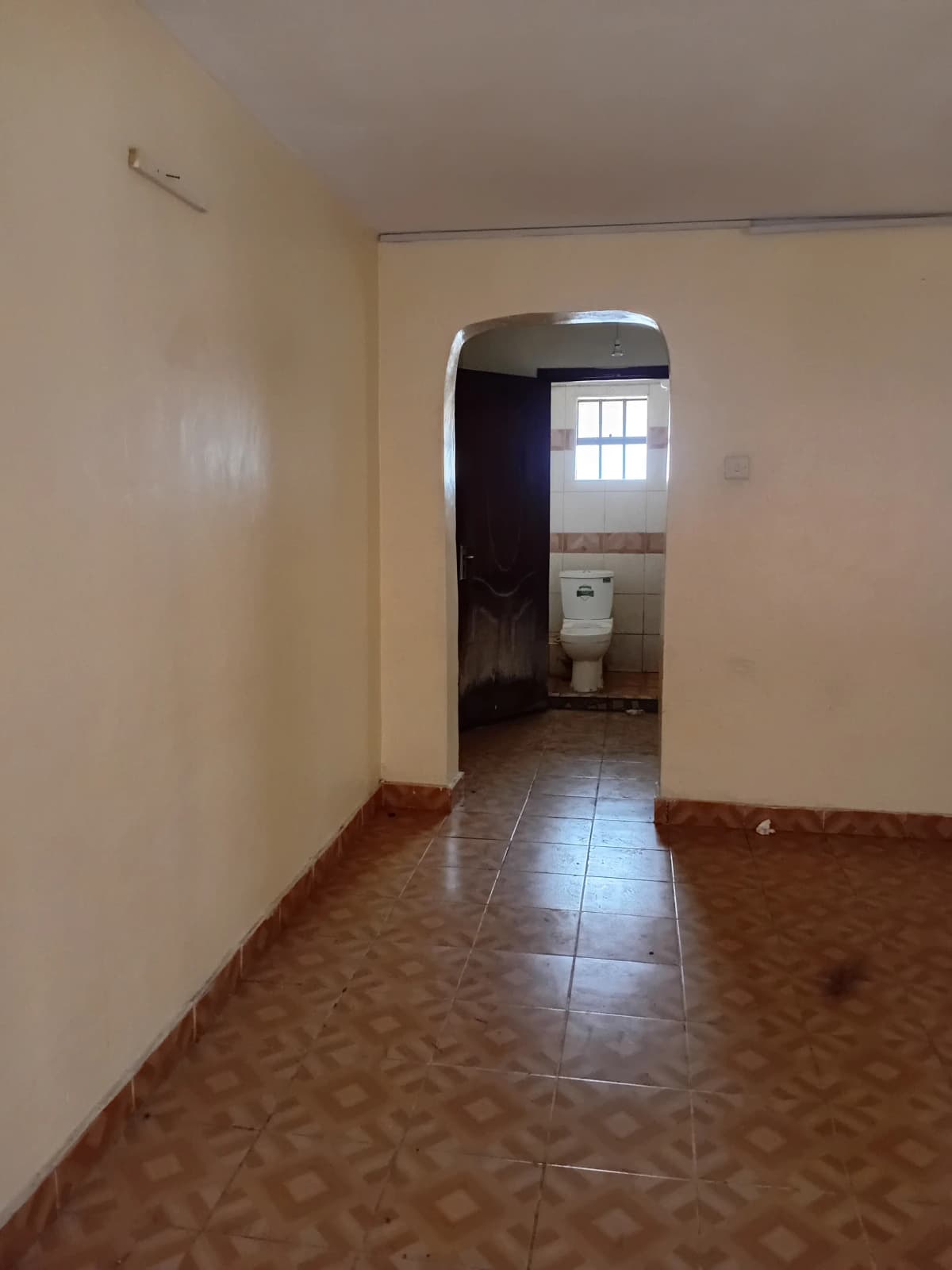 Empty corridor with terracotta tile flooring and white walls