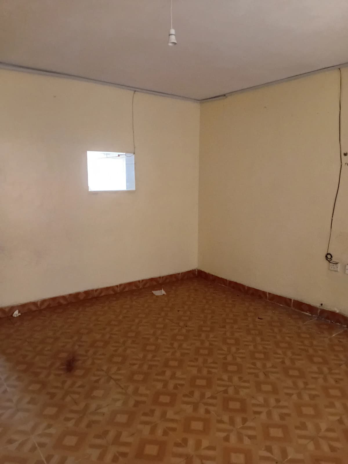 Empty bedroom with geometric patterned flooring and natural light