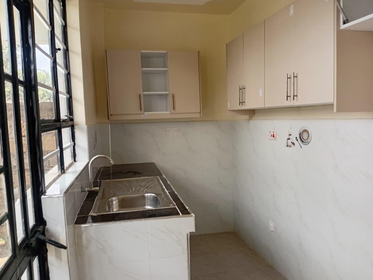 Compact kitchen with sink, white cabinetry, and natural light