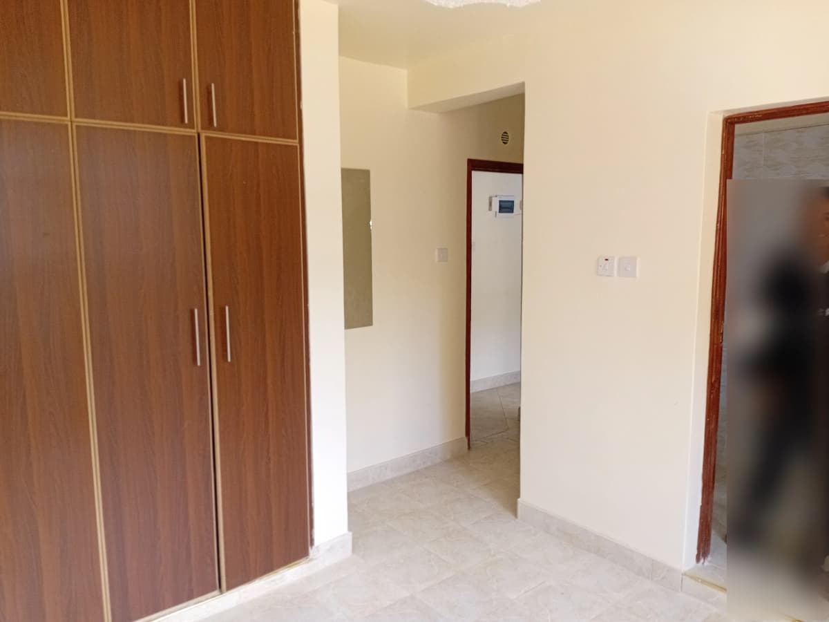 Unfurnished bedroom with wooden wardrobe and neutral walls