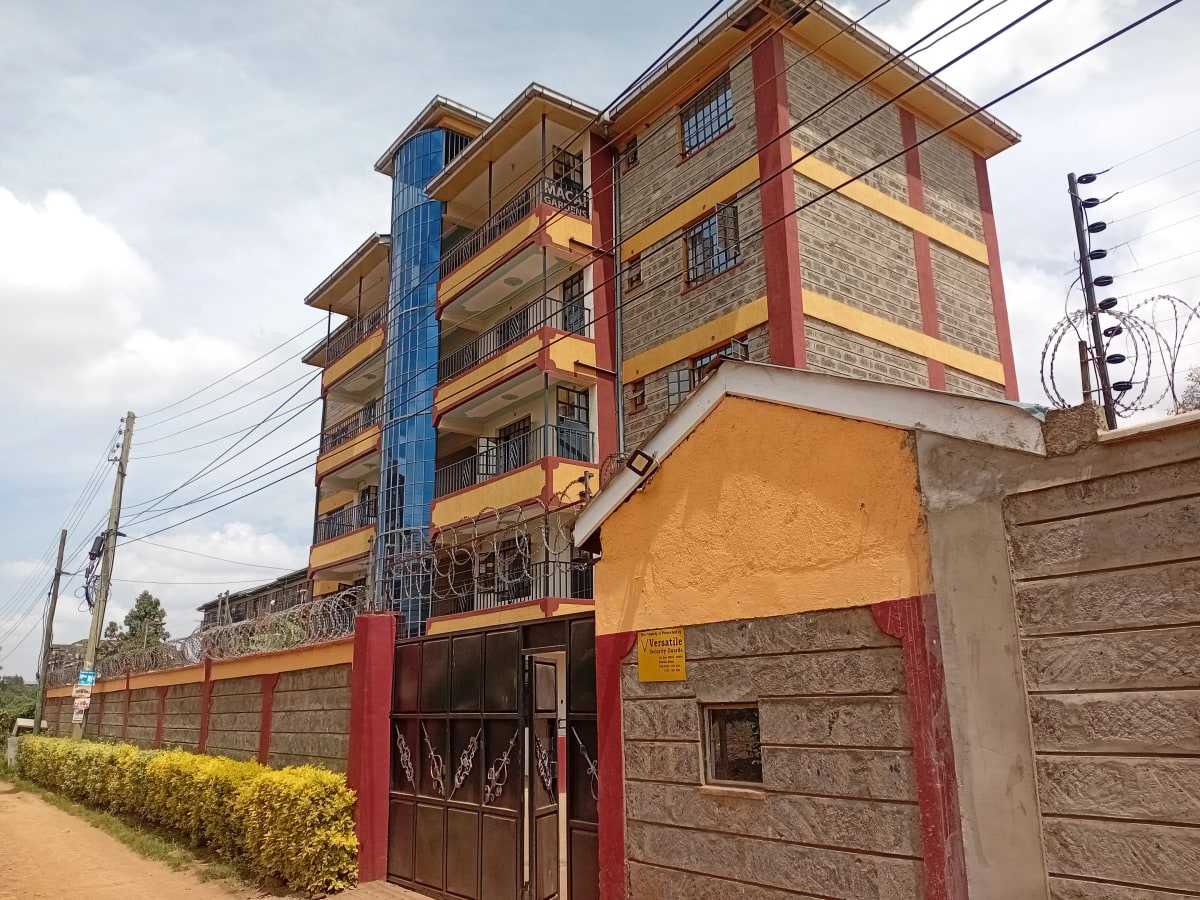 Multi-story residential building with colorful facade and compound gate