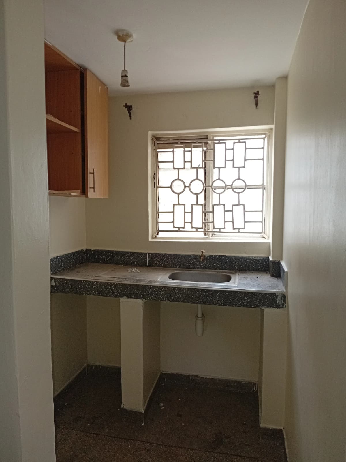 Compact kitchen with dark countertop and geometric window
