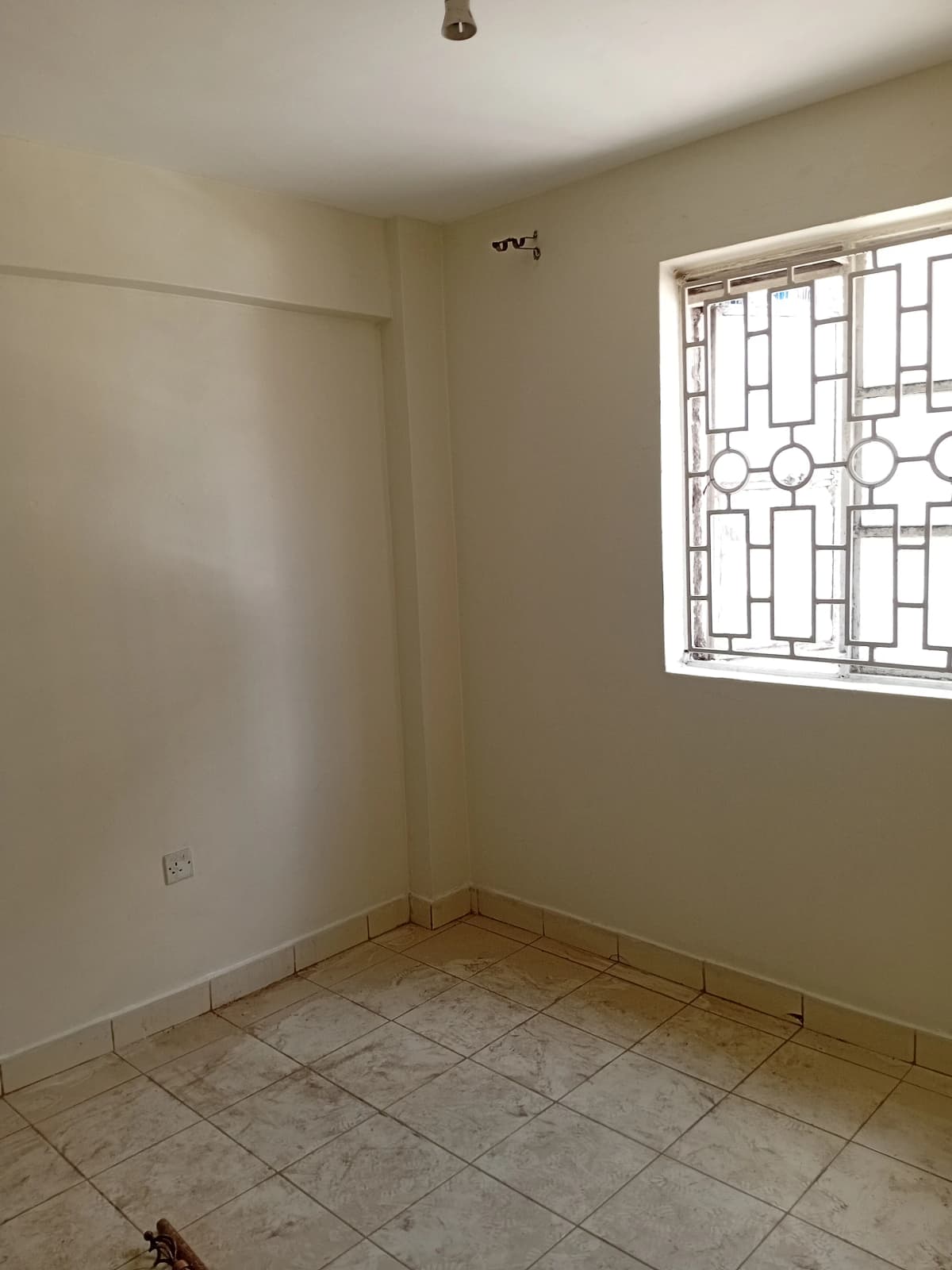 Empty bedroom with tile flooring and barred window