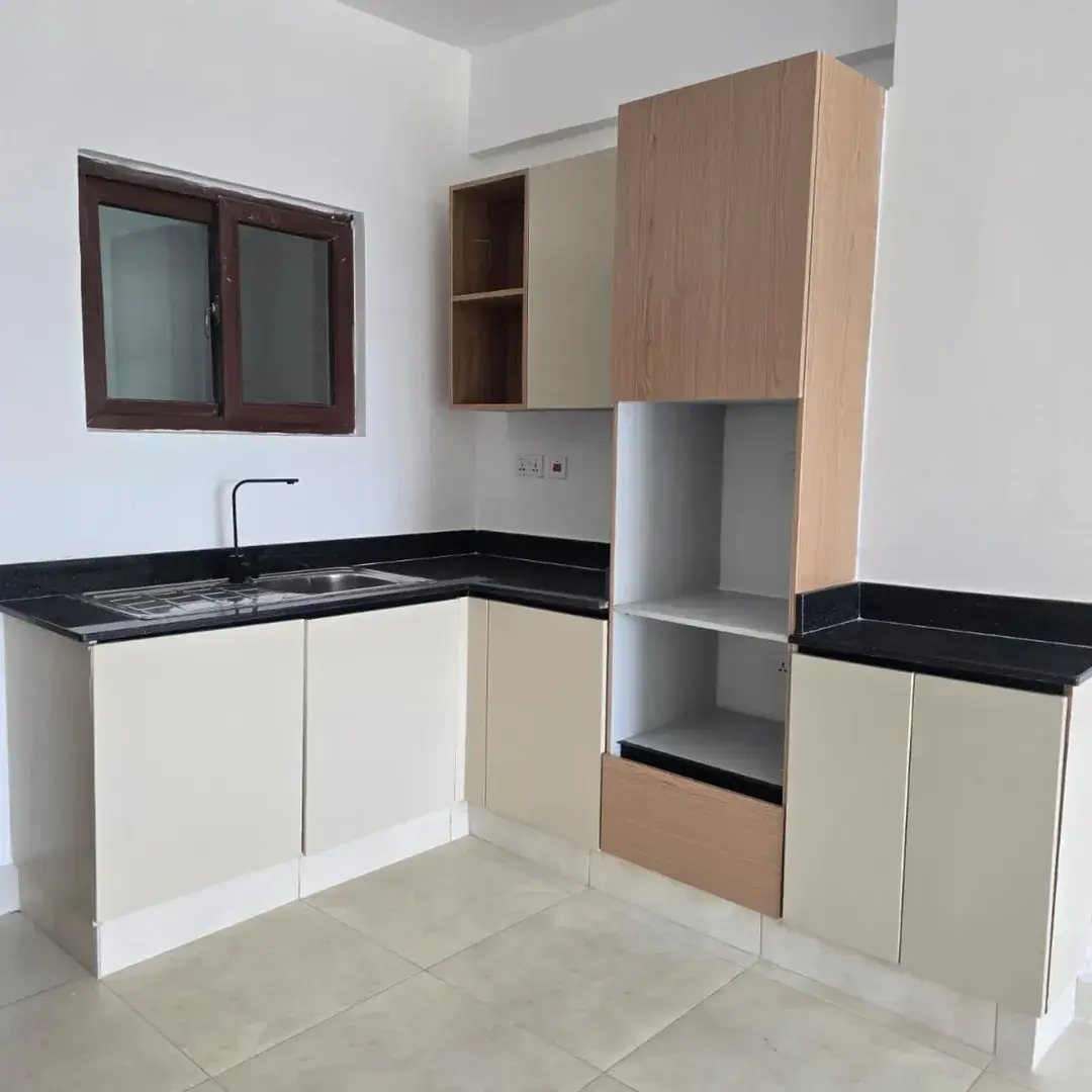 L-shaped kitchen with black granite countertops and cream cabinets