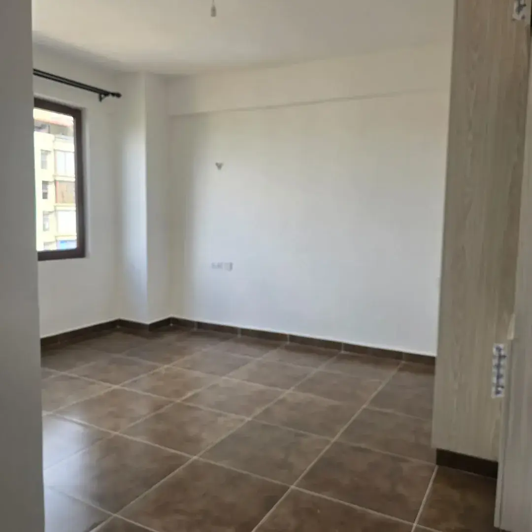 Bright unfurnished living space with tiled flooring and natural light