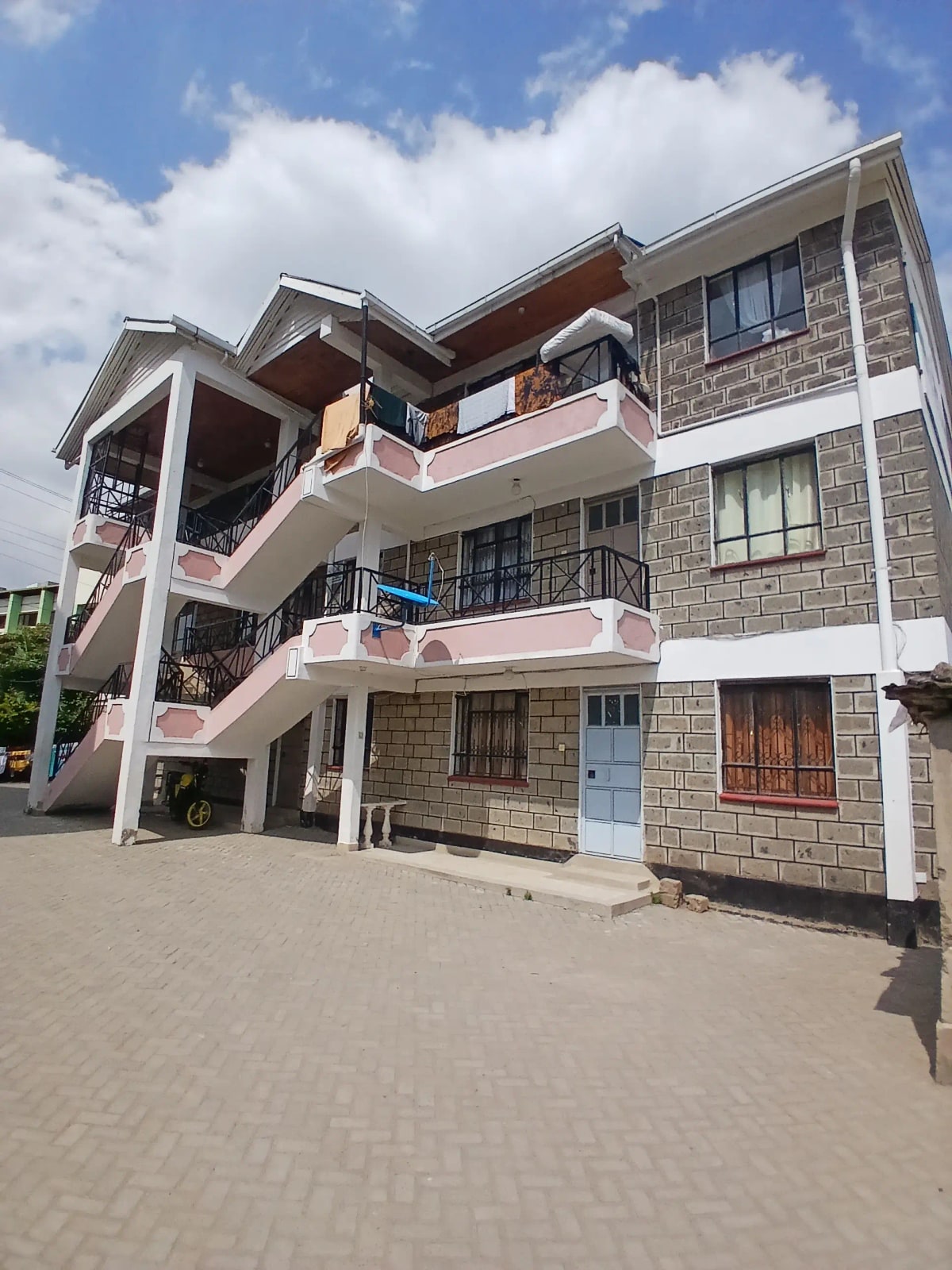 Modern multi-story residential building with pink balconies and stone facade