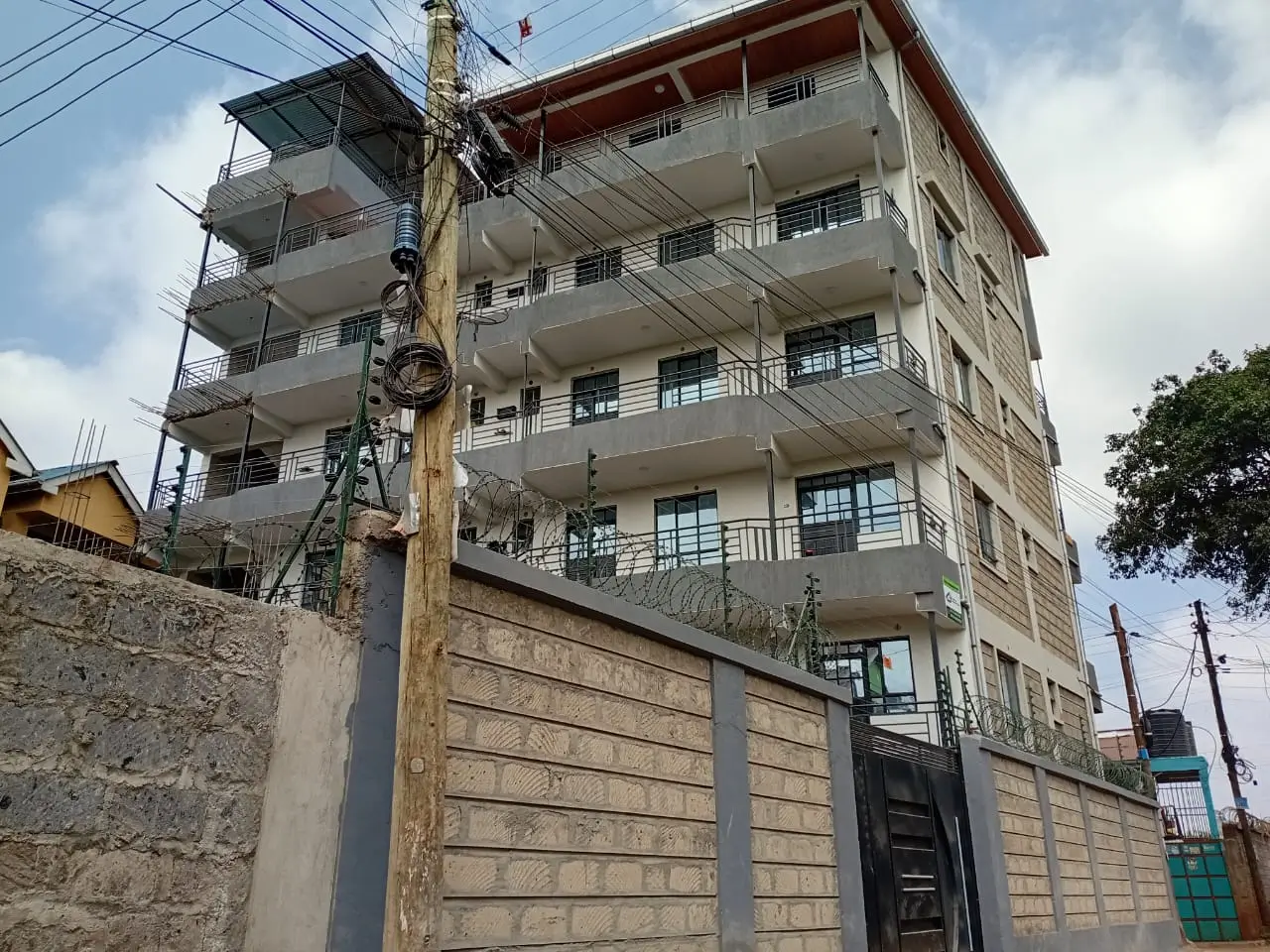 Multi-story residential building facade with balconies and boundary wall