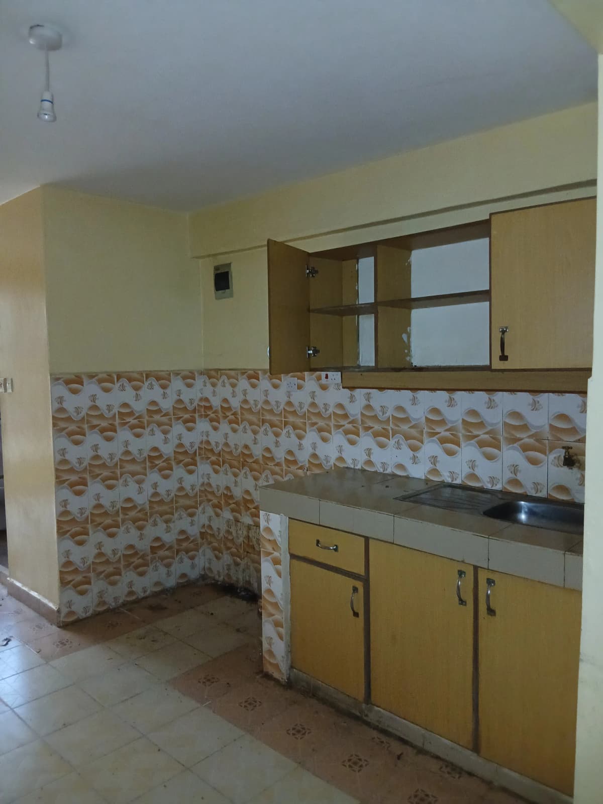 Compact kitchen with yellow cabinets and decorative tile backsplash