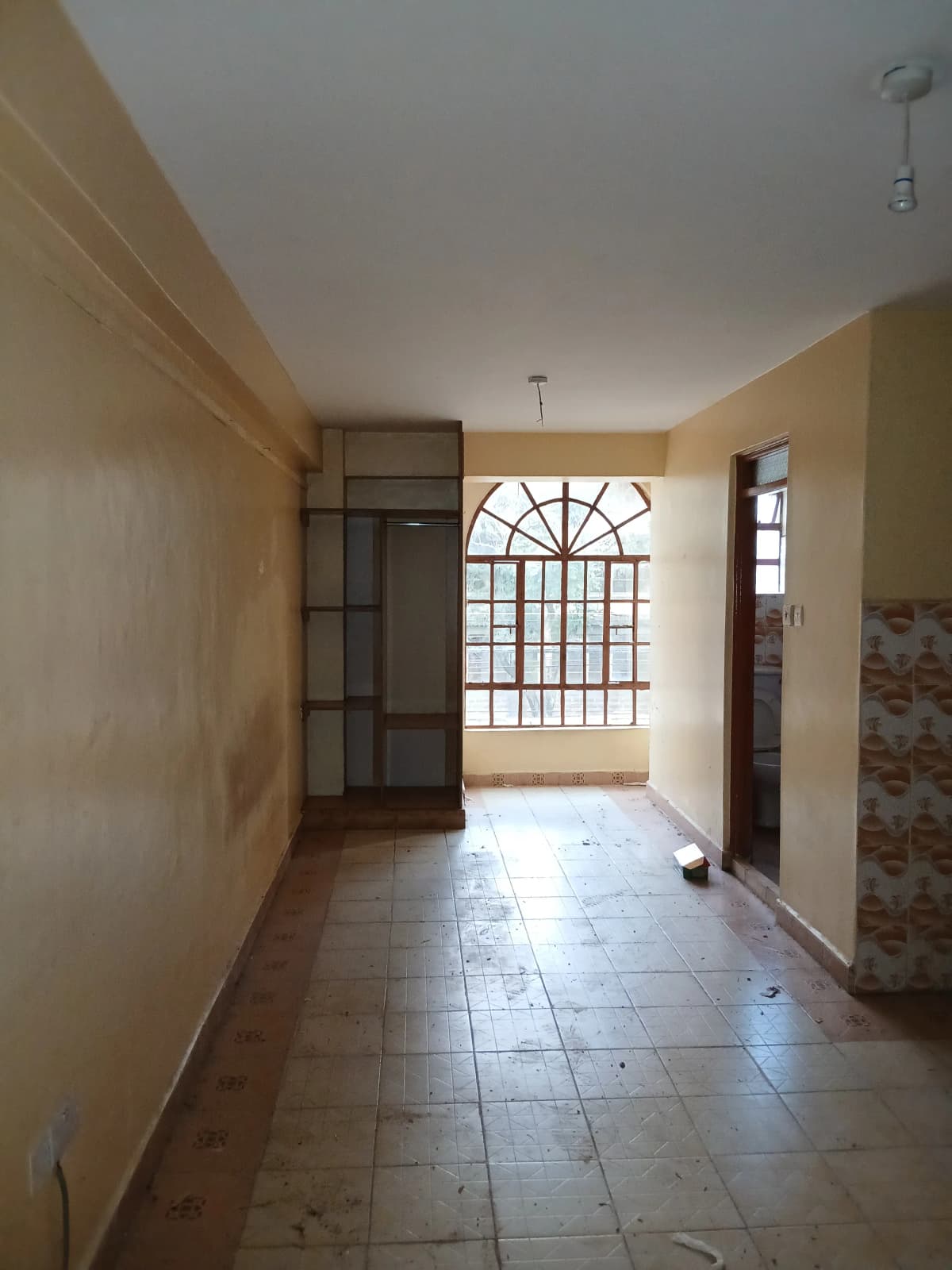 Spacious living area with barred window and tiled flooring