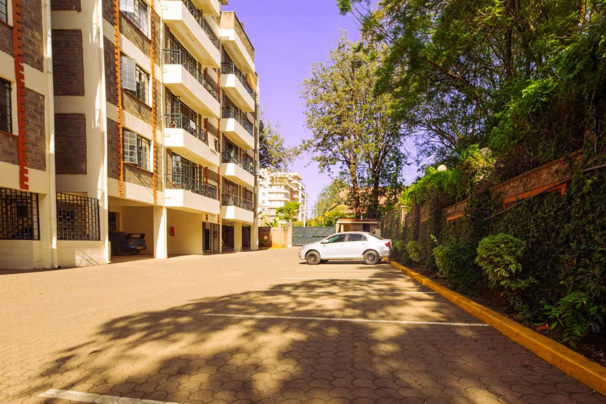 Residential compound parking area with modern apartment building