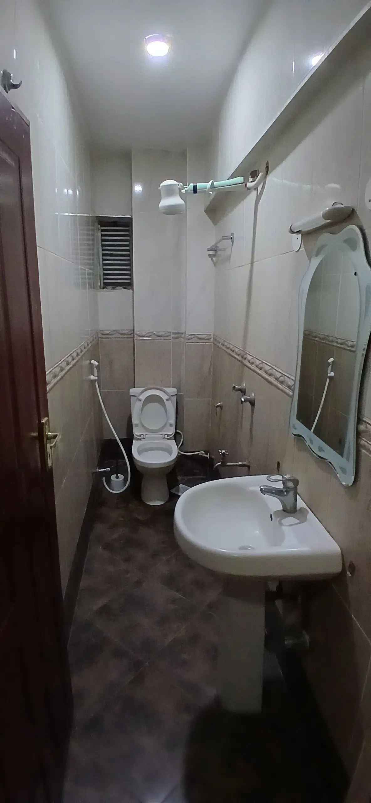 Compact bathroom with toilet, sink, and shower enclosure