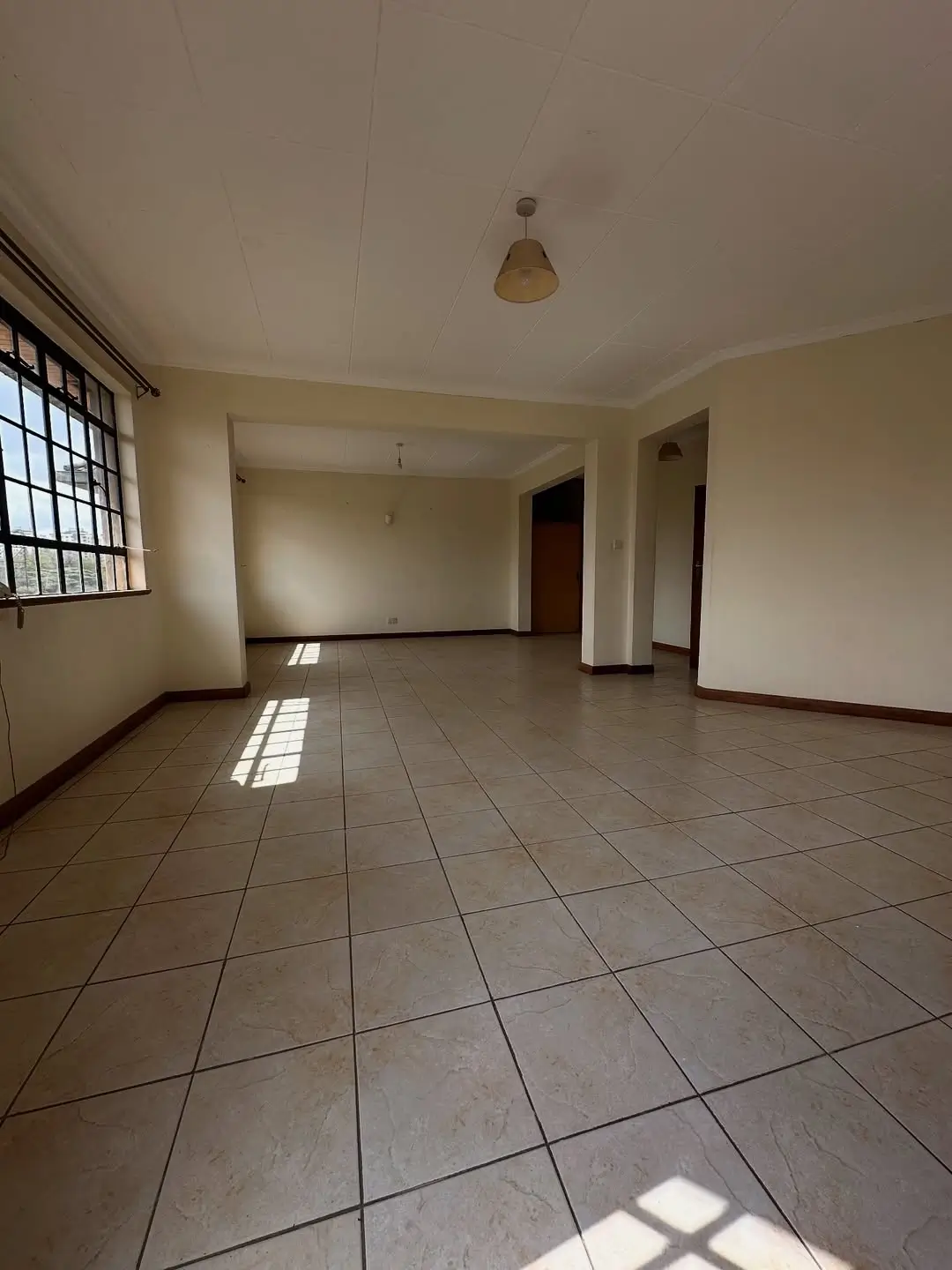 Spacious open-plan living area with tiled flooring and natural light