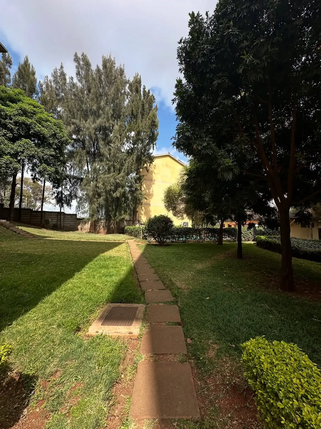 Manicured lawn with tree-lined pathway and building backdrop