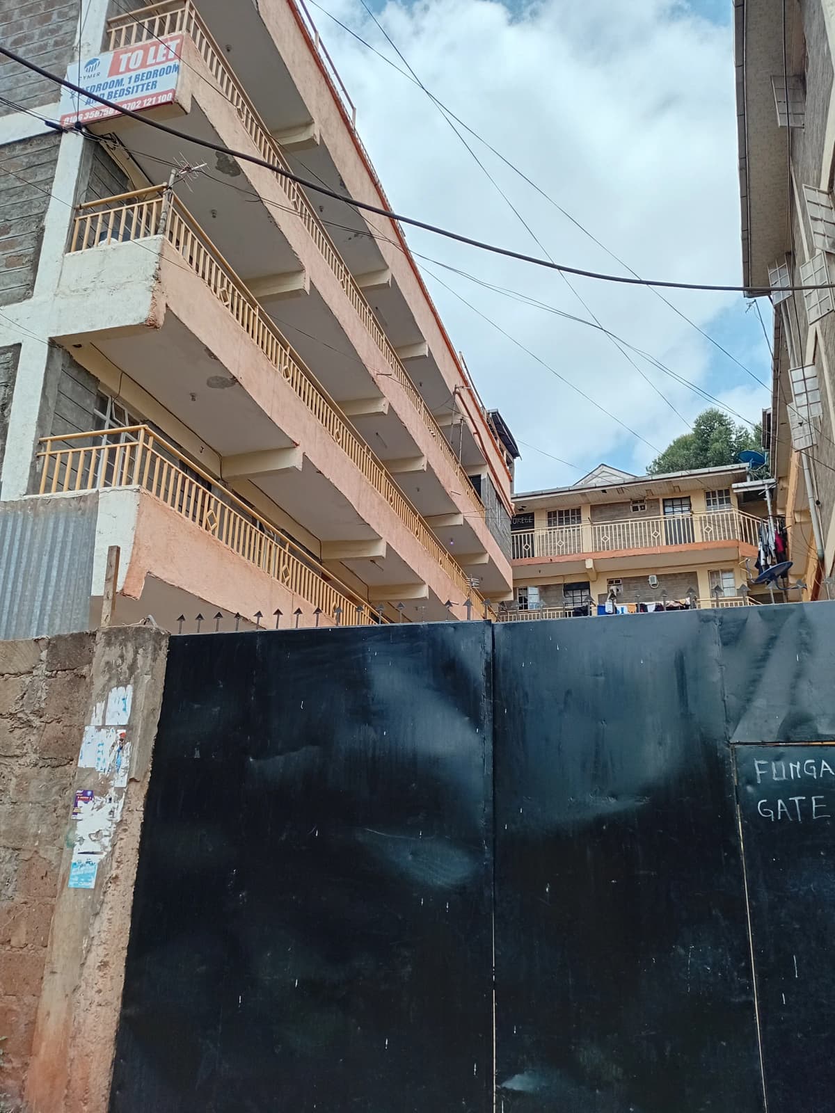 Multi-story residential building with balconies and black gate
