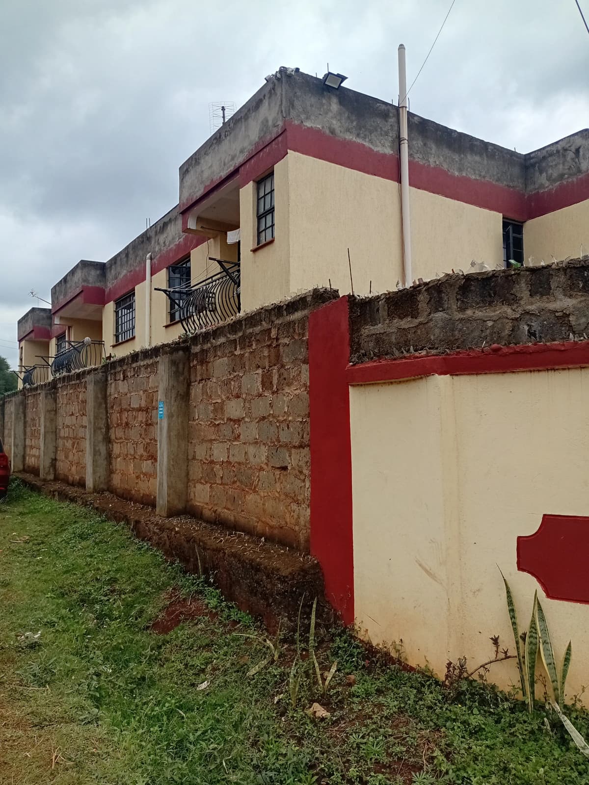Two-story residential building with red and cream facade, stone base