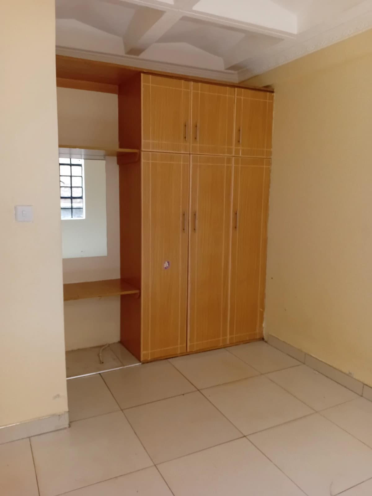 Bedroom with wooden wardrobe and tiled flooring
