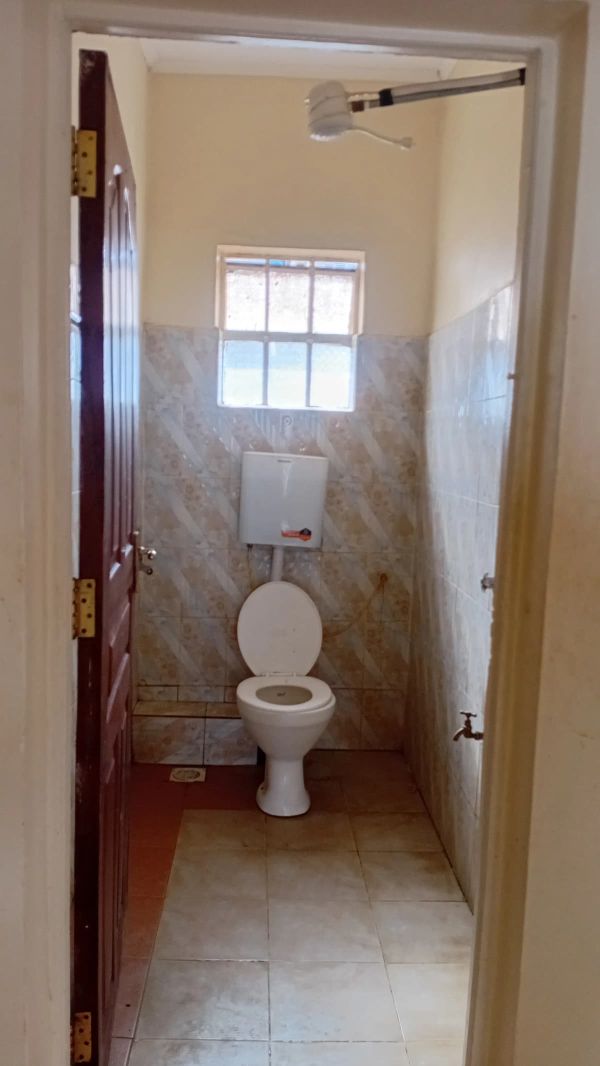 Small bathroom with toilet, window, and tiled walls