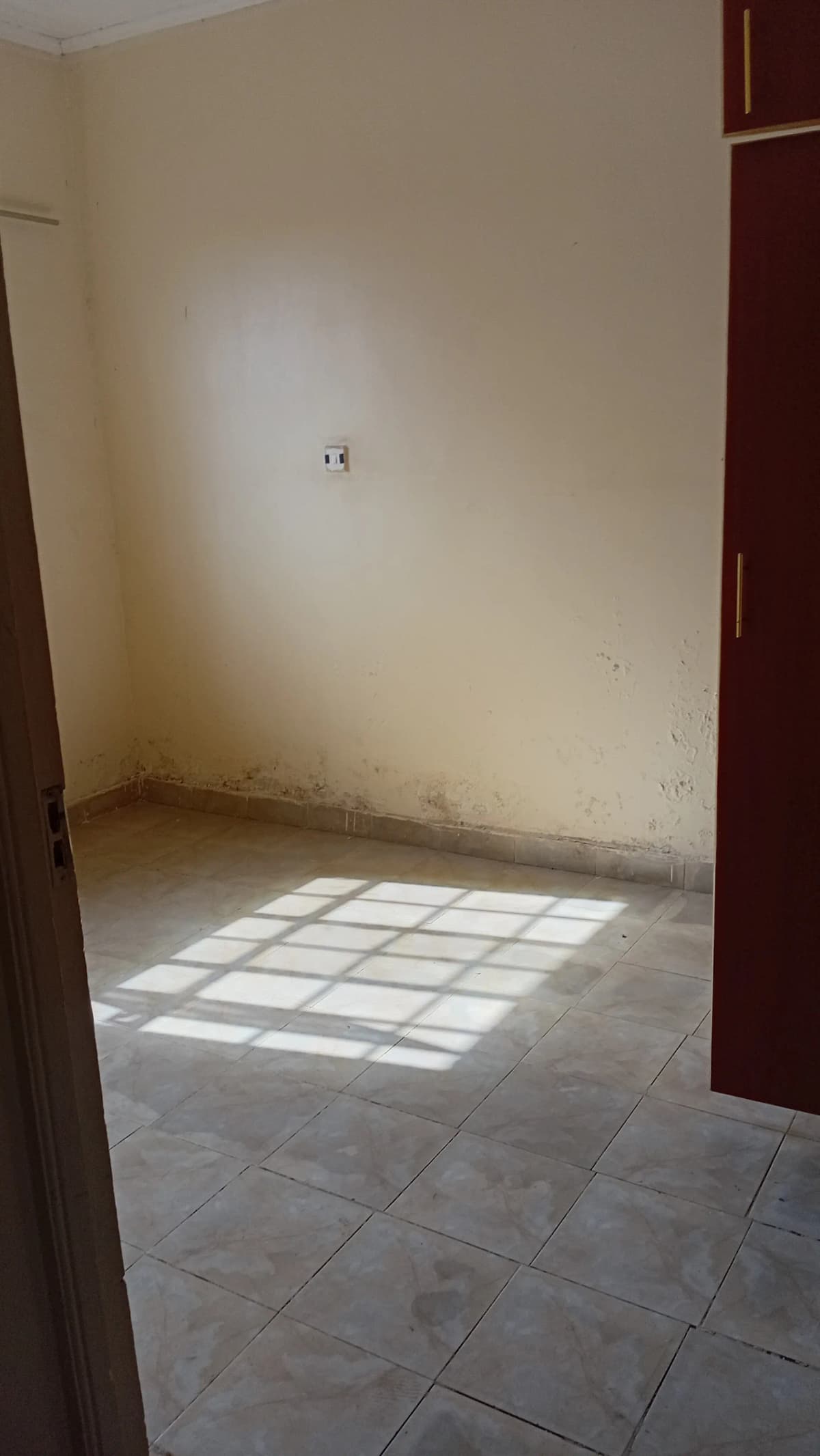 Empty bedroom with tiled floor and natural light