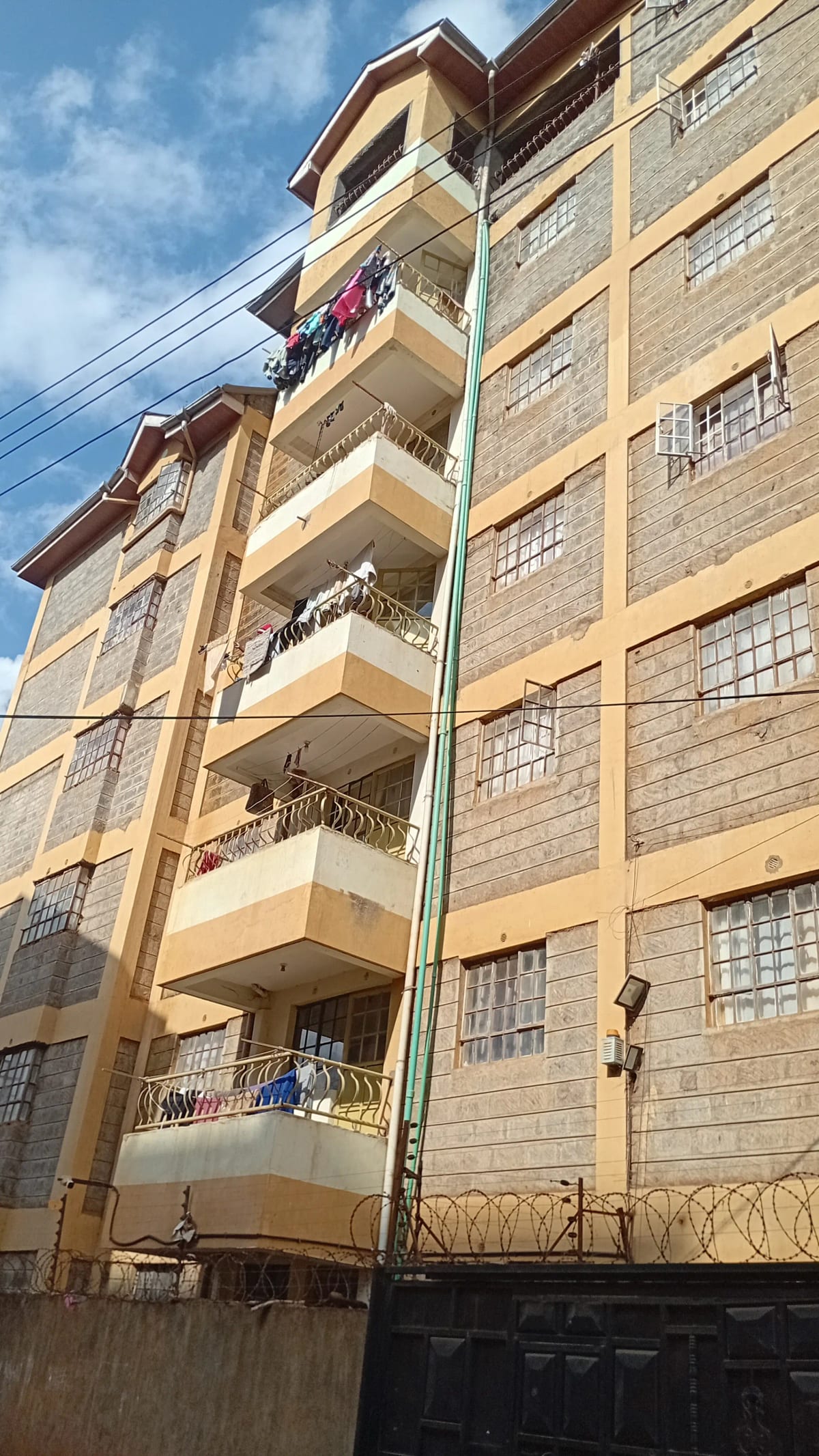 Multi-story residential building facade with balconies and compound wall