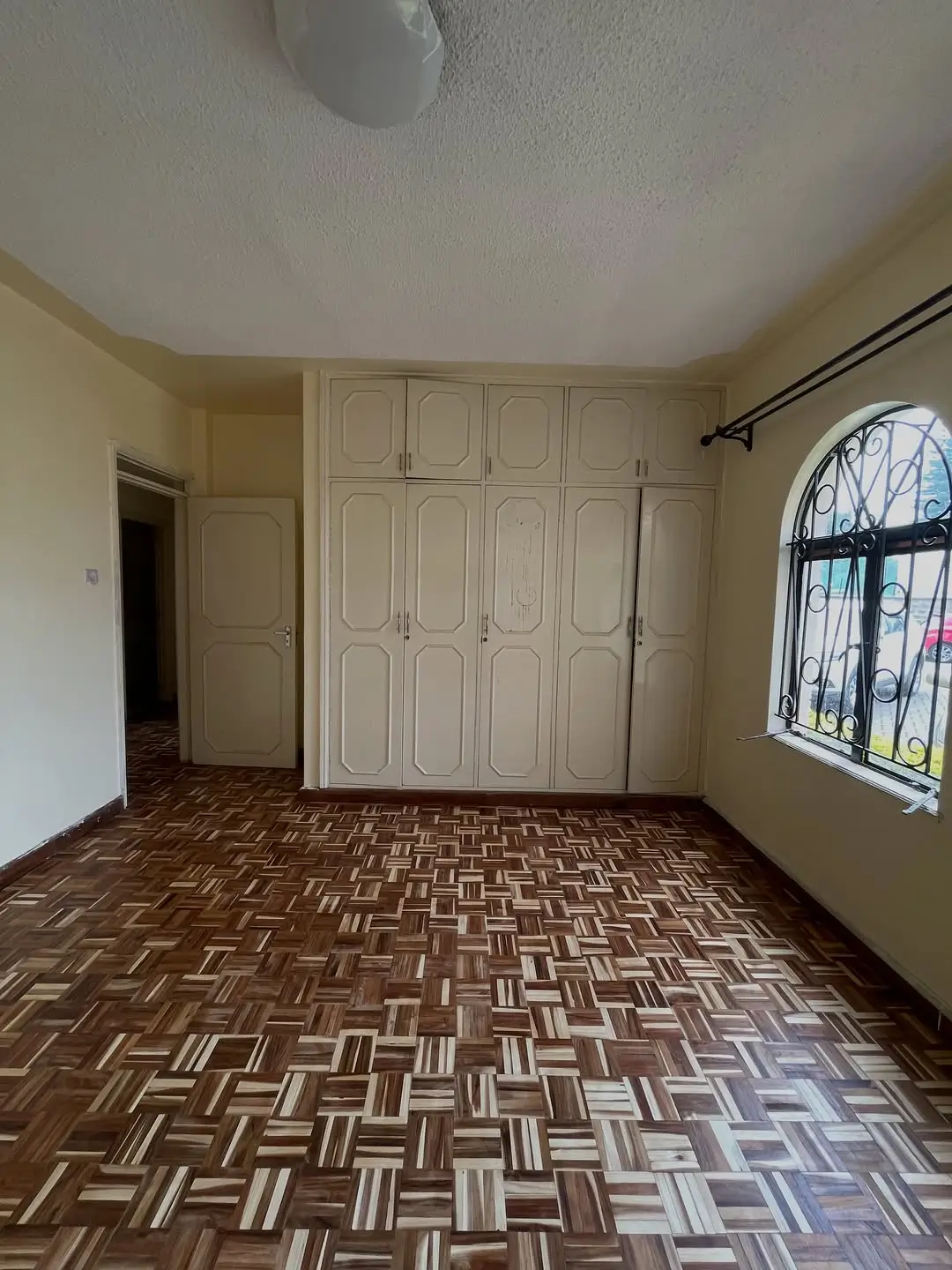 Spacious bedroom with built-in wardrobe and barred window