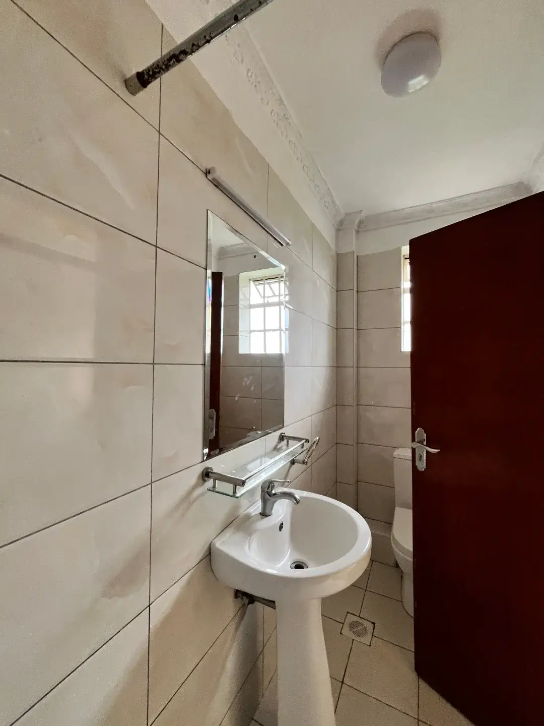 Clean bathroom with pedestal sink and large mirror