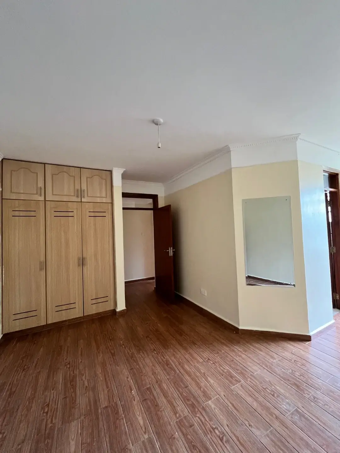 Spacious bedroom with wooden wardrobe and hardwood flooring
