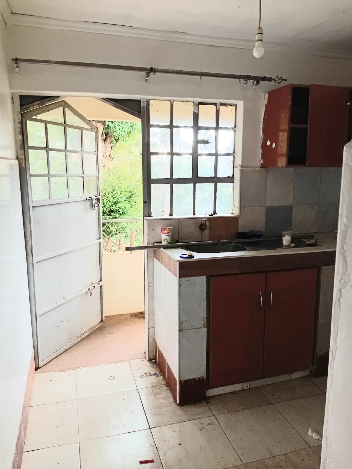 Compact kitchen with burgundy cabinets and garden access door