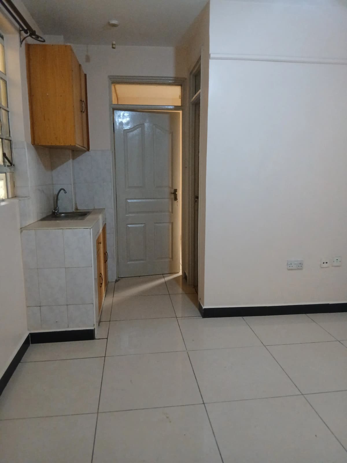 Compact kitchen with sink, wooden cabinet, tiled flooring