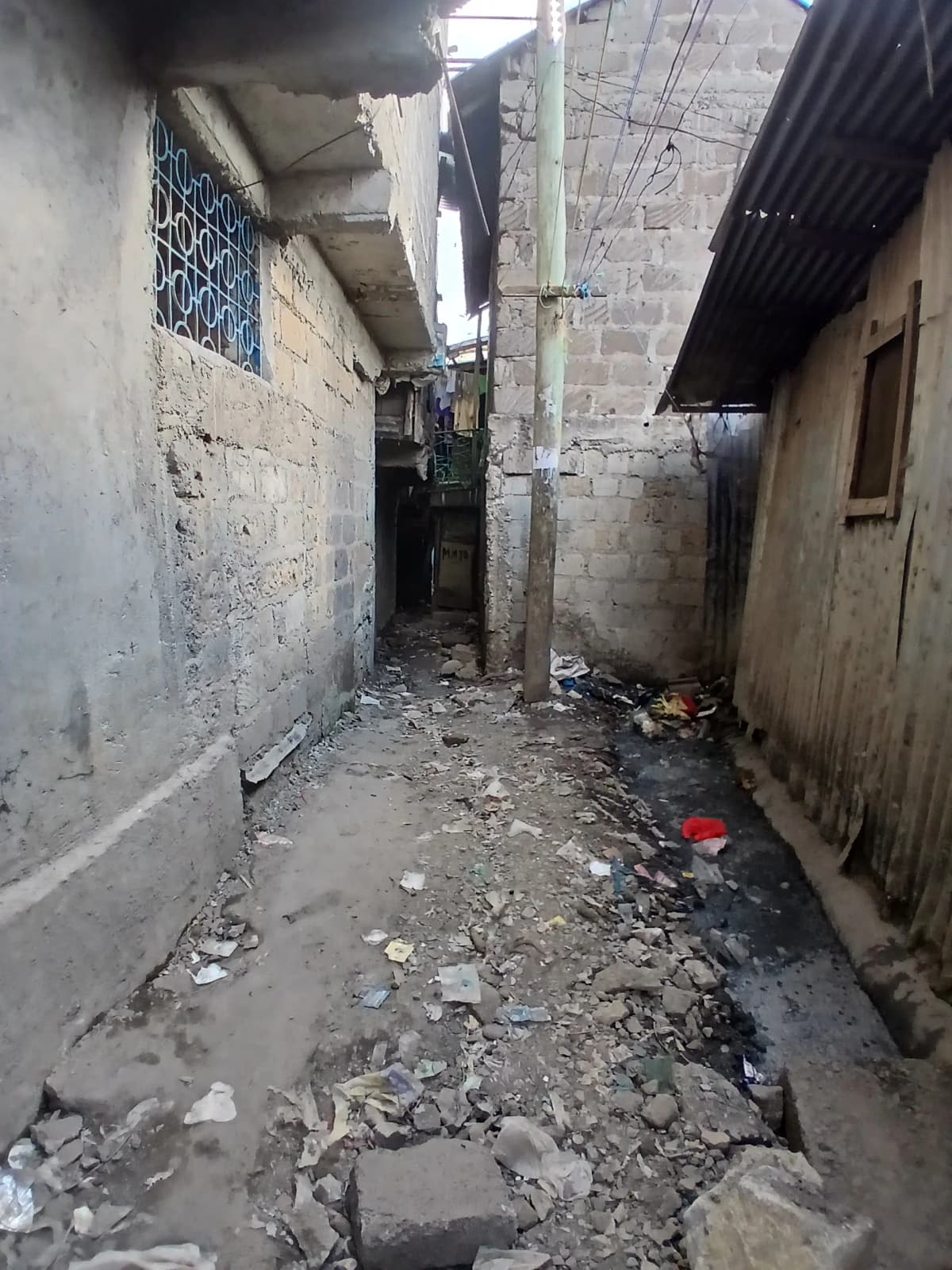 Narrow alley between residential buildings, debris scattered