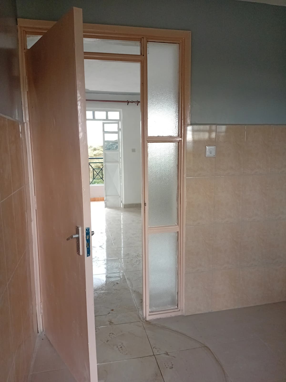 Bathroom with tiled walls and glass-paneled door entry