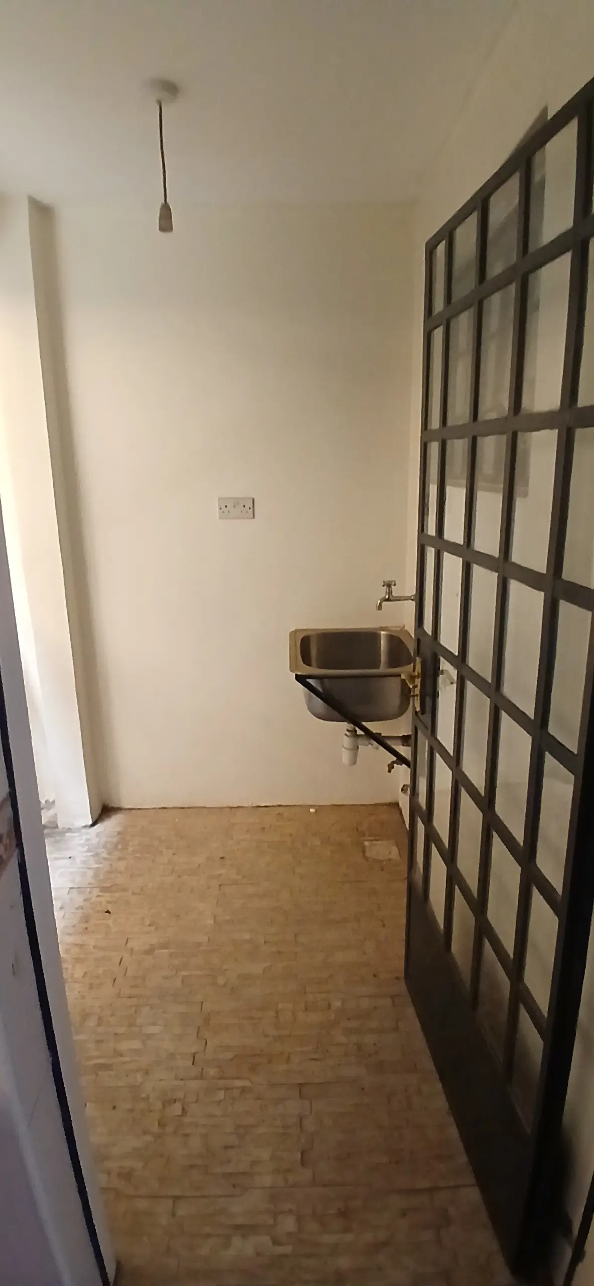 Narrow hallway with wooden floor and grid partition door